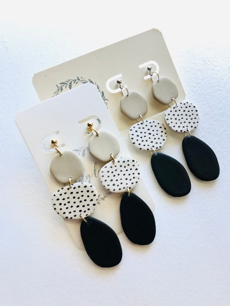 four pairs of black and white earrings with polka dots on the bottom, one is hanging from