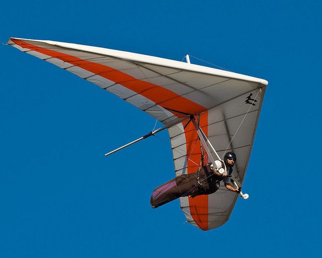 a person is flying through the air on a hang gliding plane in the blue sky