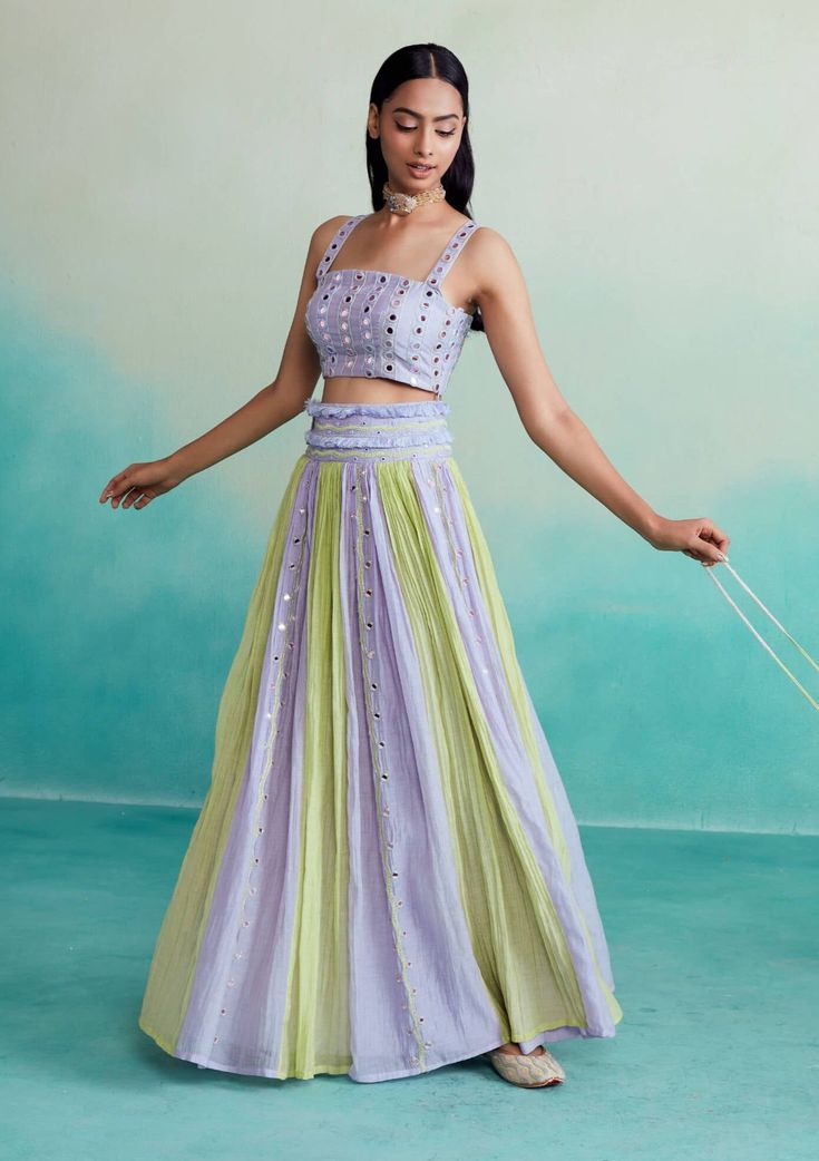 The amaya skirt top set is a delightful 3-piece ensemble in a charming lavender and lime color combination. The blouse is adorned with intricate mirror work hand embroidery on both the front and back, adding a touch of elegance to your look. The skirt features beautiful paneling with mirror work and comes with an embroidered belt adorned with tassels and more mirror work, creating a flattering silhouette that's sure to turn heads. To complete the set, we've included a stunning shisha embroidery Paneling With Mirror, Designer Summer Party Wear Sets, Summer Party Wear Designer Sets, Pista Green Bollywood Dress For Spring, Bollywood Style Pista Green Dress For Spring, Designer Summer Sets In Floor-length, Summer Reception Embellished Lehenga, Designer Floor-length Sets For Summer, Green Summer Dresses For Reception