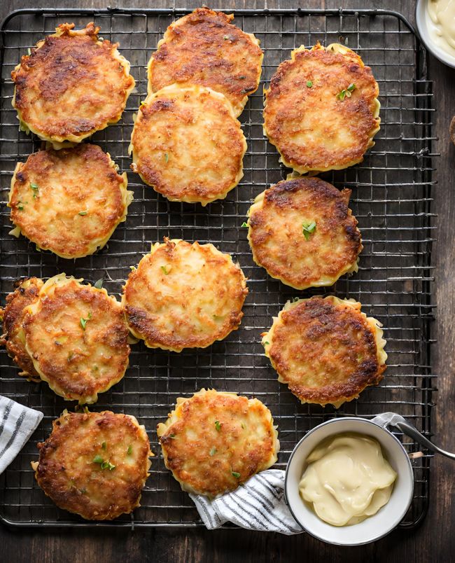 several crab cakes on a cooling rack with sauce