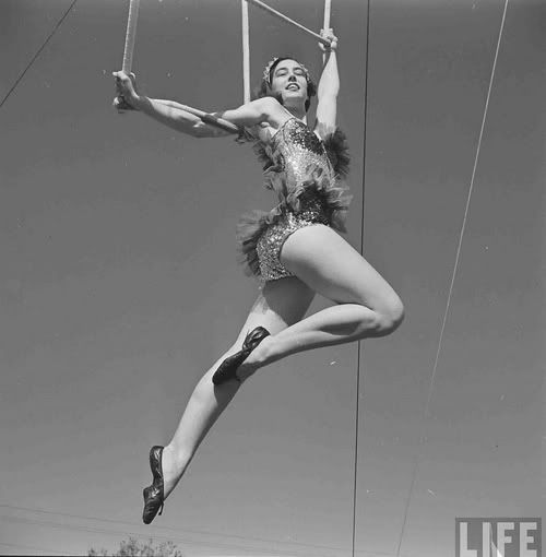 a woman is performing aerial acrobatic tricks on a rope in an old photo