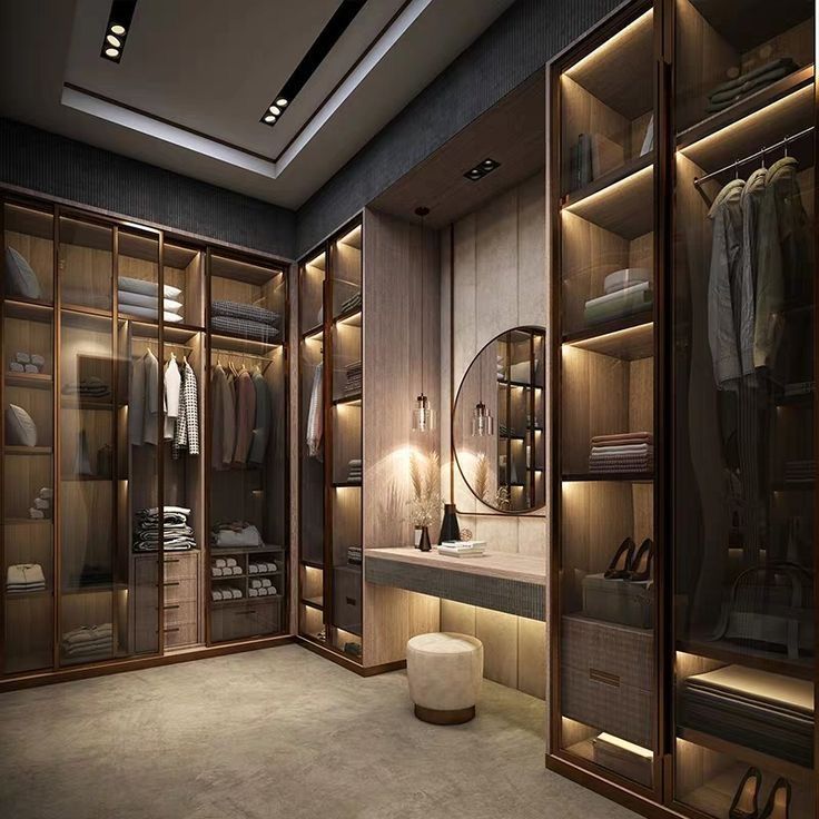 a large walk in closet with lots of clothes on shelves and lights hanging from the ceiling