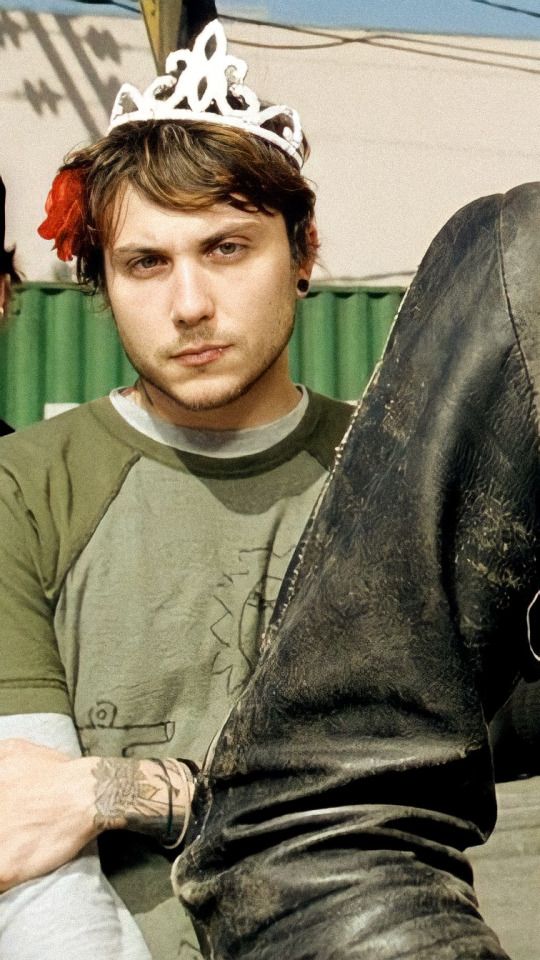 a man with a crown on his head sitting next to a pair of black boots