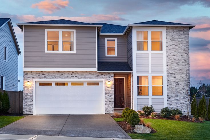 a two story house with white and gray sidings at dusk in front of a cloudy sky