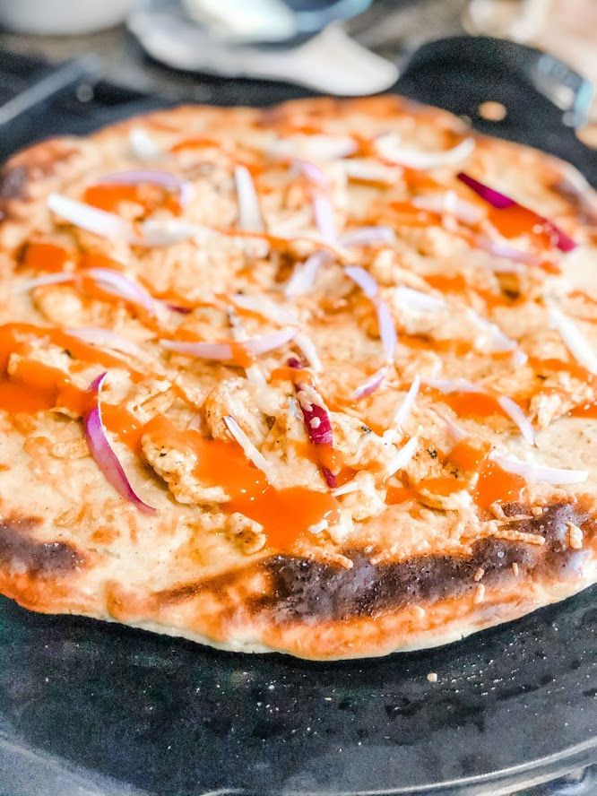 an uncooked pizza sitting on top of a metal pan covered in cheese and onions