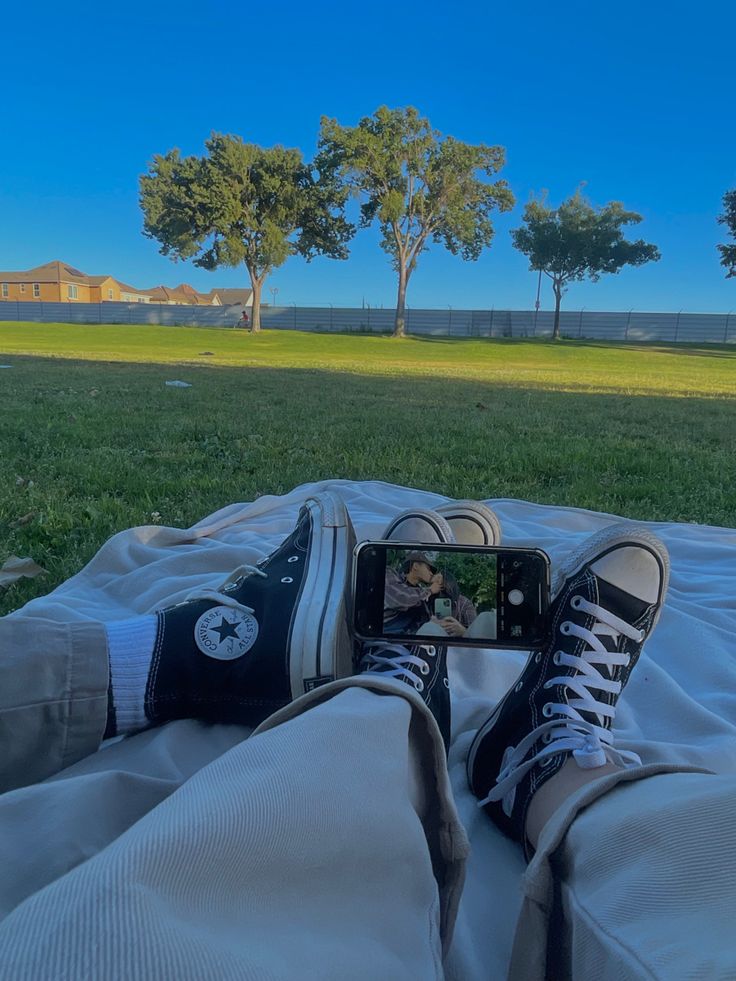 someone is taking a photo with their cell phone on the blanket in front of some trees