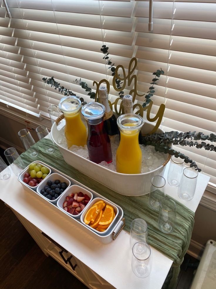 there is a tray with fruit and juices on the table next to some glasses