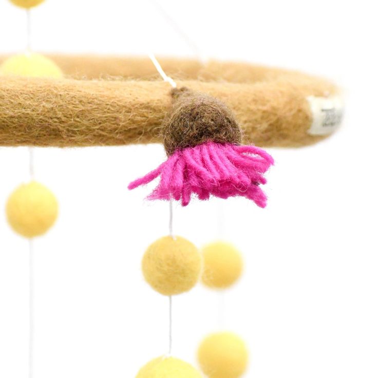 a close up of a pink flower on a branch with balls hanging from the branches