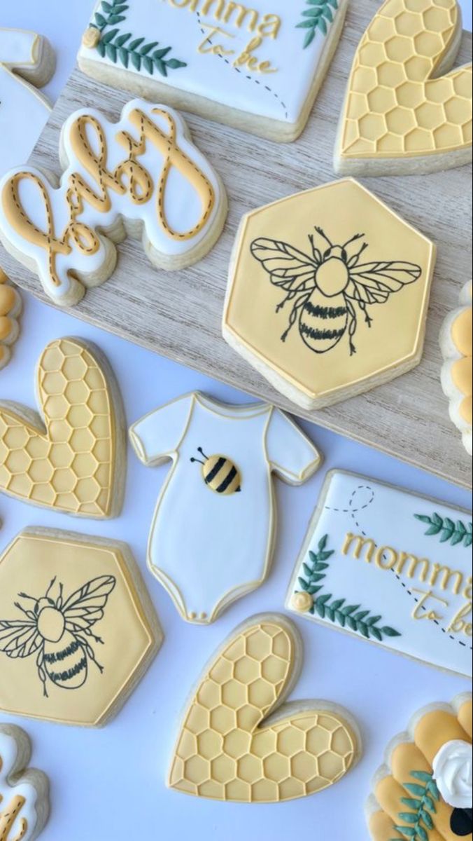 decorated cookies with bees and honeycombs are displayed on a white tablecloth,