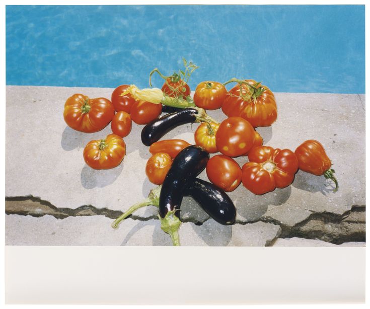 a group of vegetables sitting on top of a stone wall next to a swimming pool