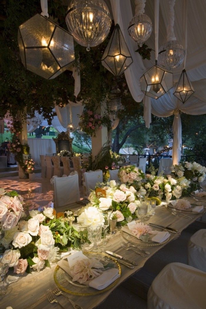 a long table is set up with flowers and candles for an elegant wedding reception at night