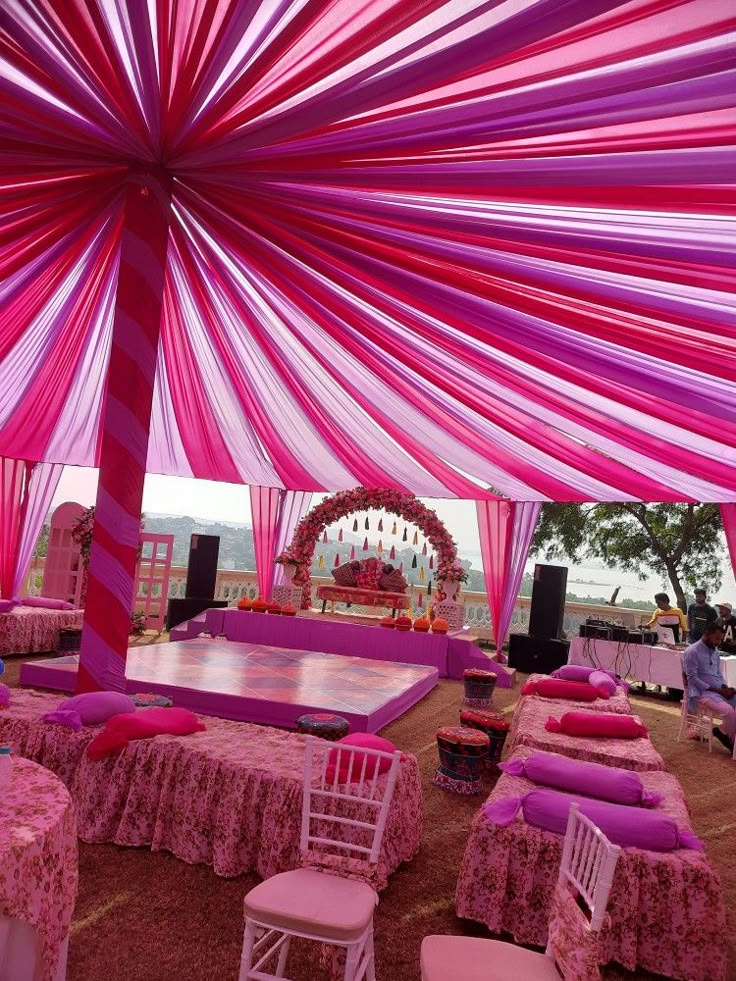 an outdoor event with pink and purple decorations on the dance floor, tables and chairs