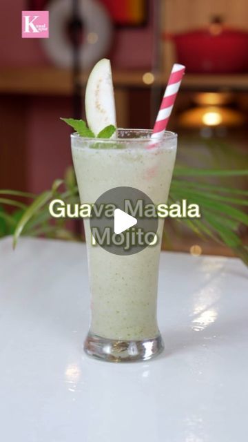 a smoothie is sitting on a table with a straw in the cup and some green leaves sticking out of it