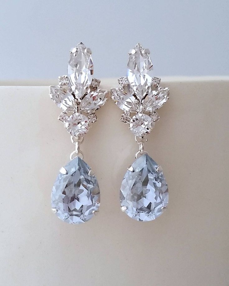 two pairs of earrings with crystal stones on top of each earring, one in the shape of a flower