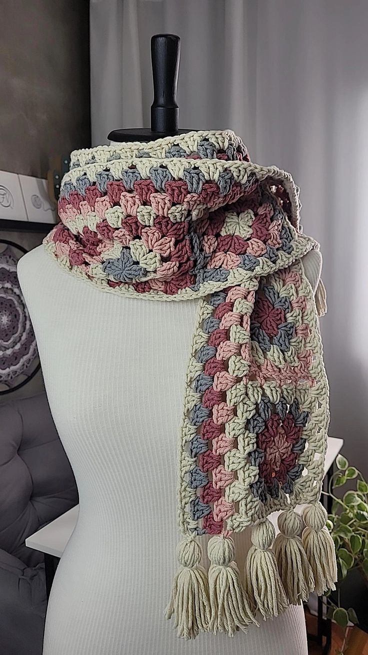 a white mannequin wearing a multicolored crocheted scarf