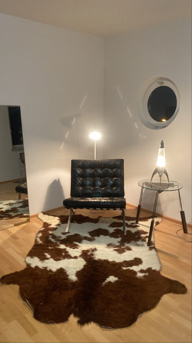 a living room with a cowhide rug on the floor and a chair in front of it