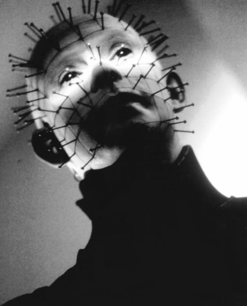 a man with spiked spikes on his head in the dark, looking up at something