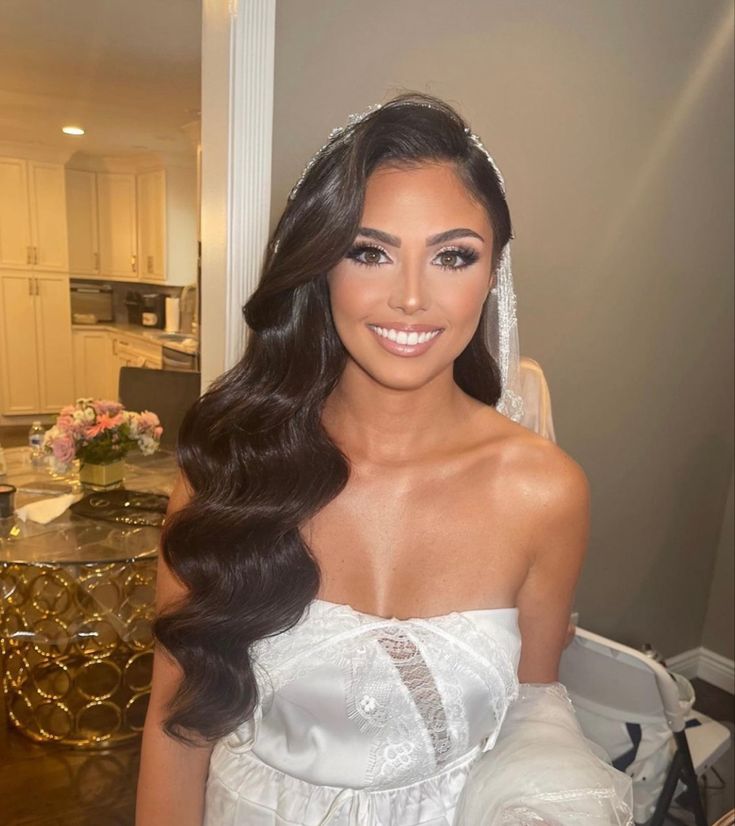 a woman in a wedding dress posing for the camera with her long hair and veil over her head