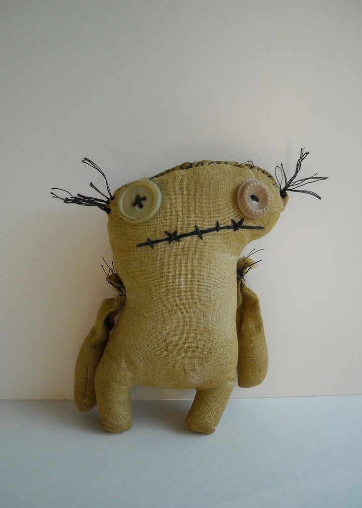 a yellow stuffed animal with barbed wire on it's head and eyes, sitting in front of a white wall