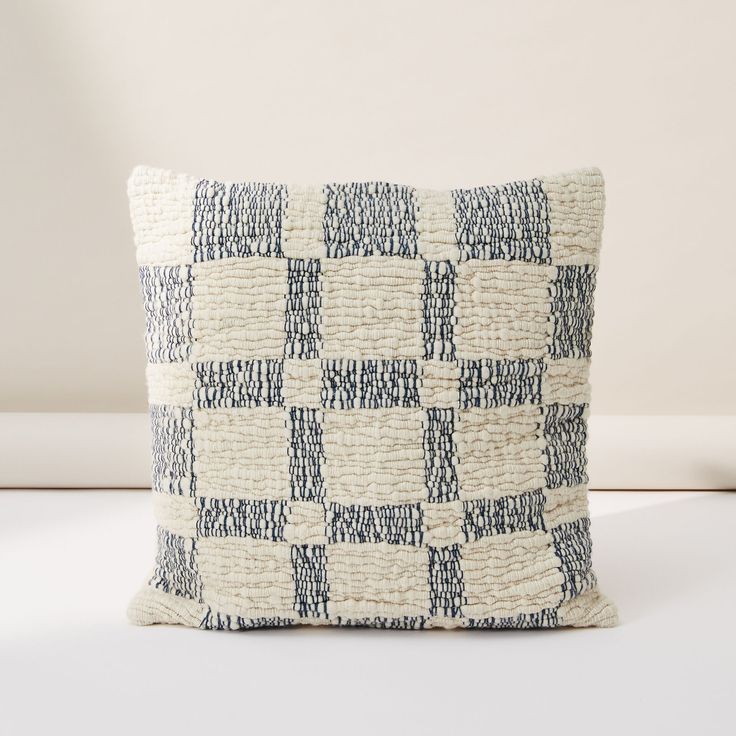 a black and white checkered pillow sitting on top of a table next to a wall