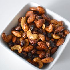 a white square bowl filled with nuts on top of a table