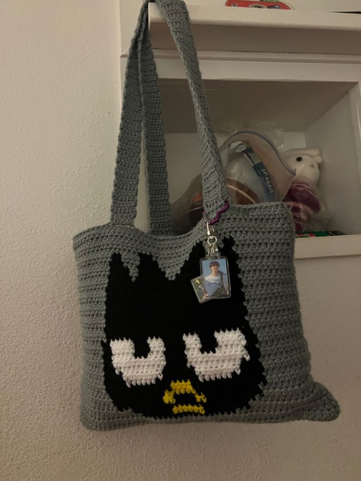 a crocheted tote bag with a black cat on the front and white eyes