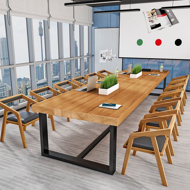 a large wooden table with chairs around it in front of a whiteboard and windows