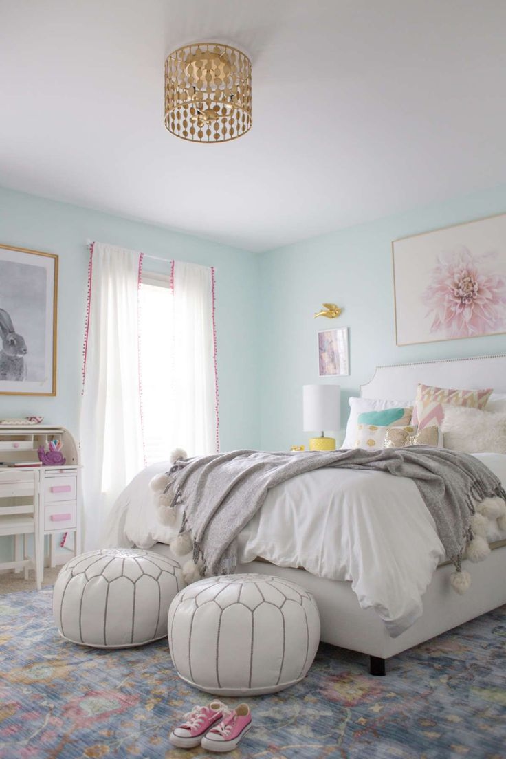 a bed room with a neatly made bed and two foot stools on the floor