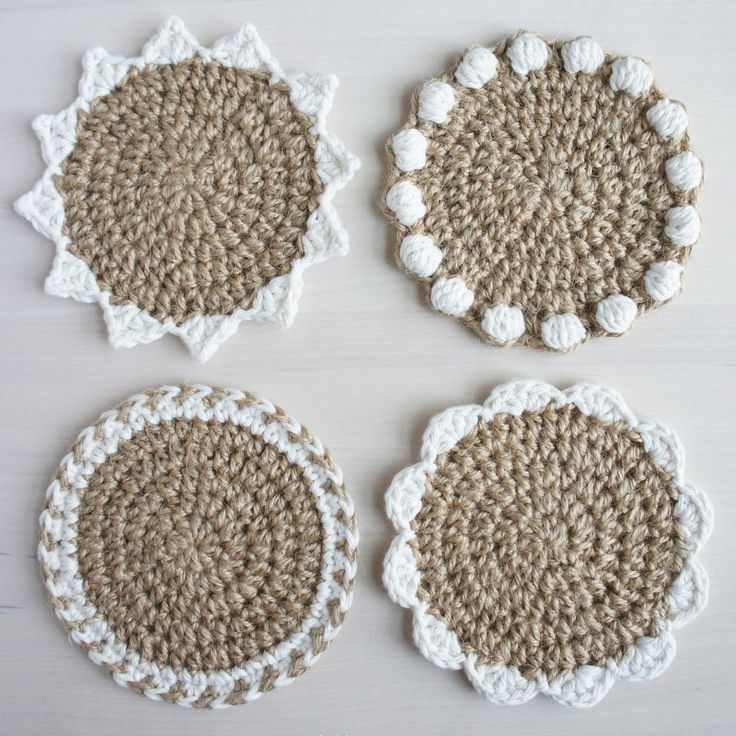 four crocheted coasters on a table with white and brown trim around them