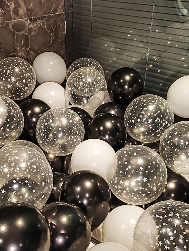 some black and white balloons are in a ball pit with silver stars on the top