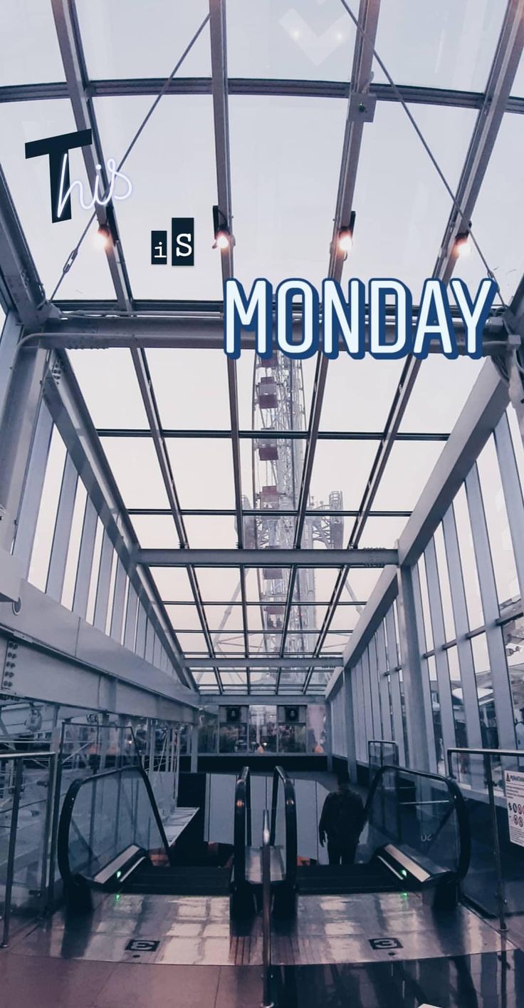 there is a sign that says monday in the middle of an airport terminal with people walking through it