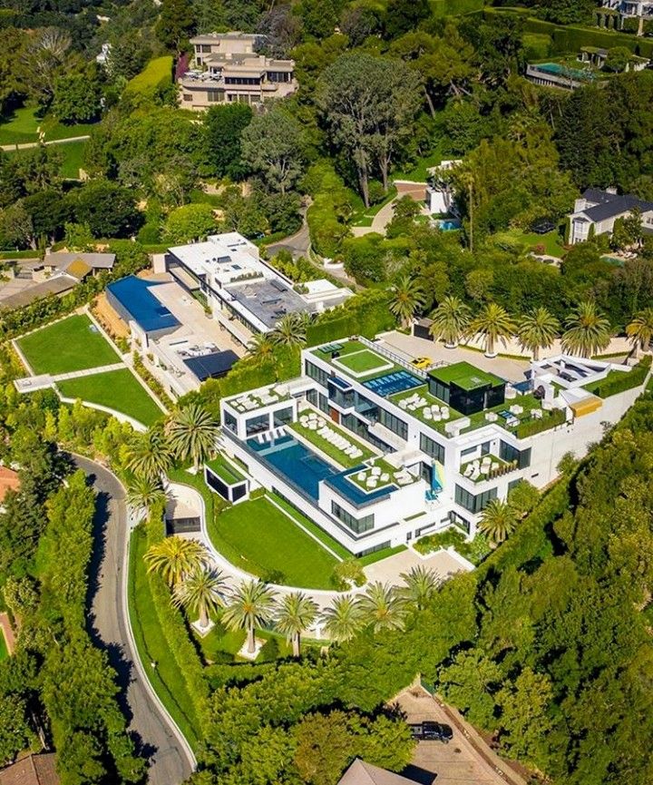 an aerial view of a large house surrounded by lush green trees and greenery in the foreground