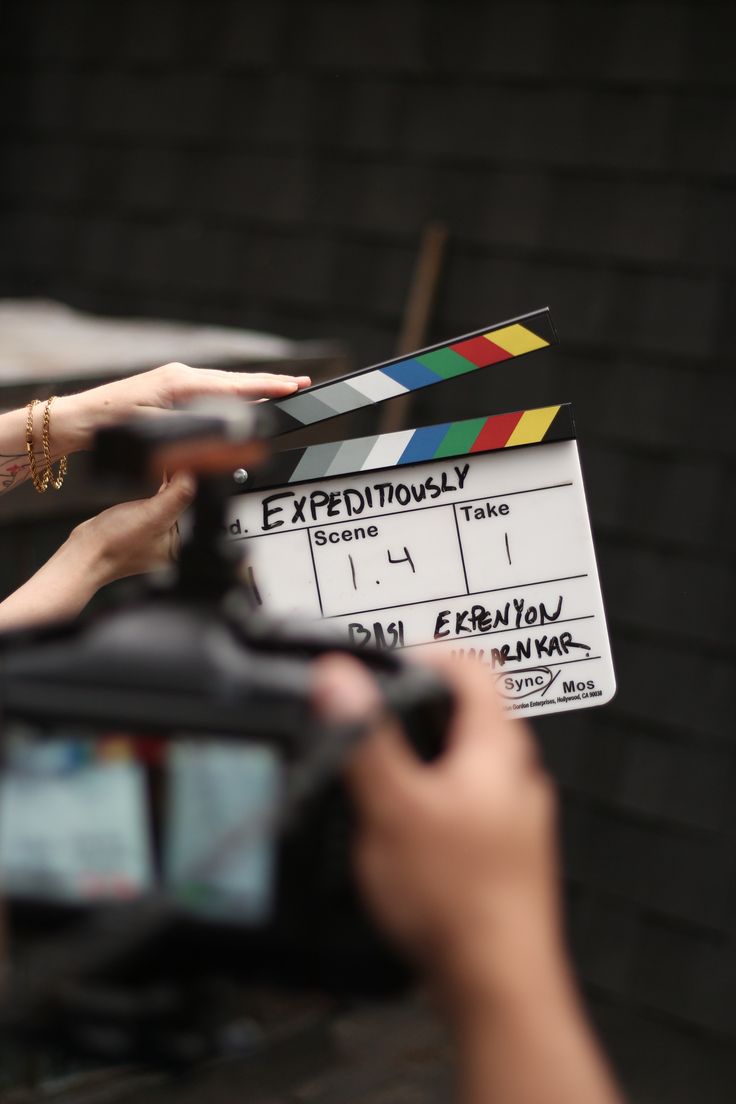 a person holding a camera near a movie clapper