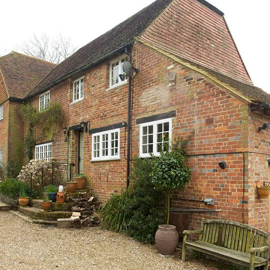 an old brick building with a wooden bench in the foreground and potted plants on either side