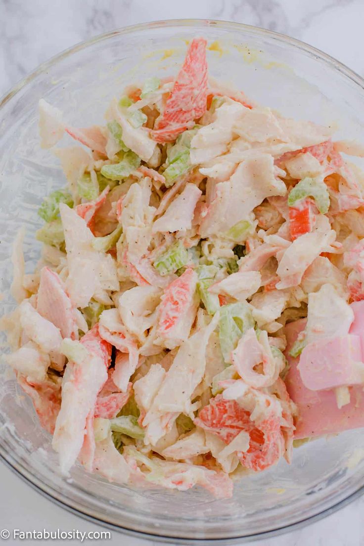 a glass bowl filled with chicken salad on top of a table