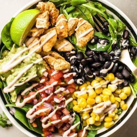 a salad with chicken, lettuce, black beans, corn and avocado