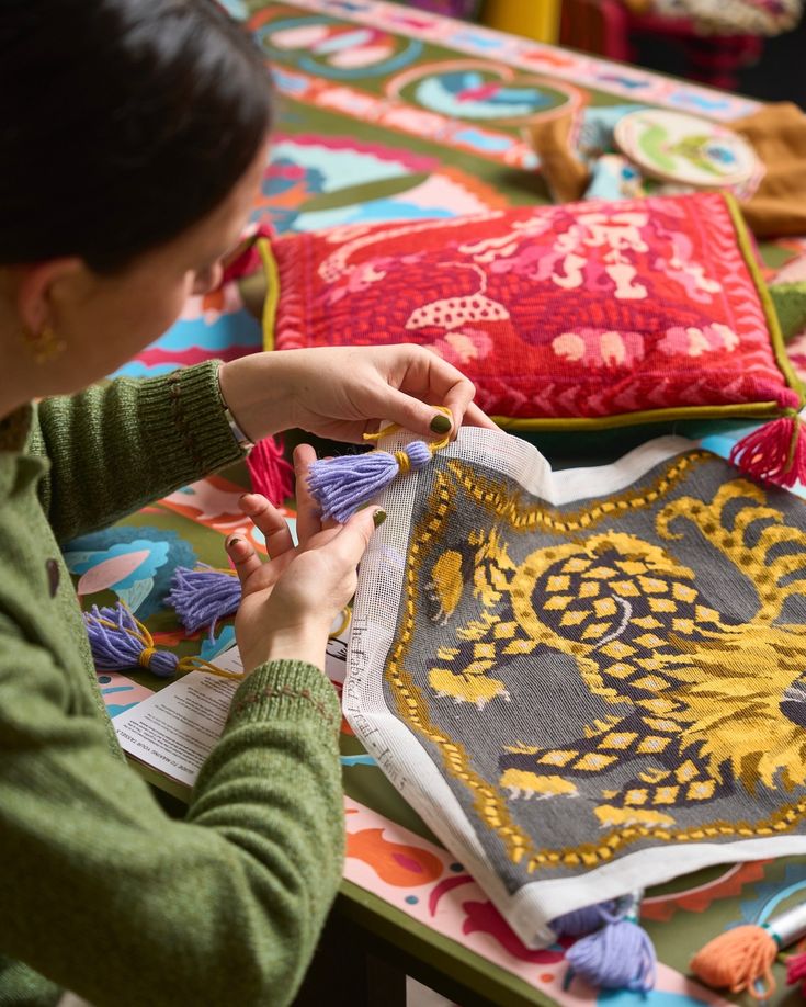 a woman is working on an embroidered cloth