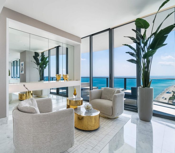 a living room filled with furniture and large windows overlooking the ocean in front of it