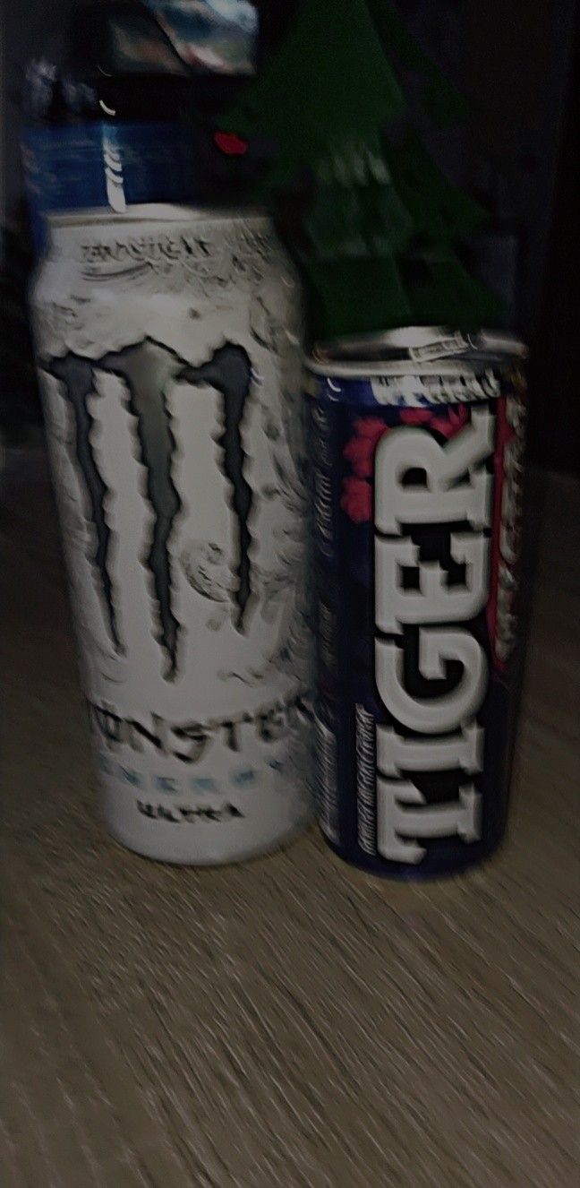 two cans sitting on top of a wooden table next to each other, one with the word monster written on it