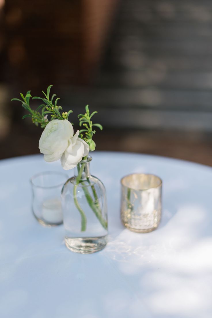 two clear vases with flowers in them on a white table cloth covered tablecloth