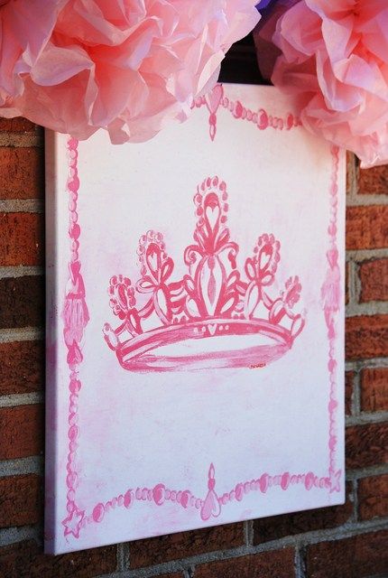 some pink tissue flowers are hanging on a brick wall and there is a drawing of a tiara