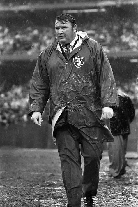 an old black and white photo of a man in rain gear walking on the field