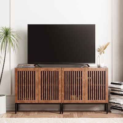 an entertainment center with a large television on it's stand in front of a potted plant