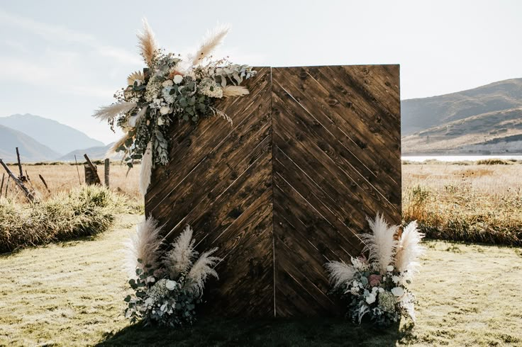 a wooden structure with white flowers and feathers on it in the middle of a field