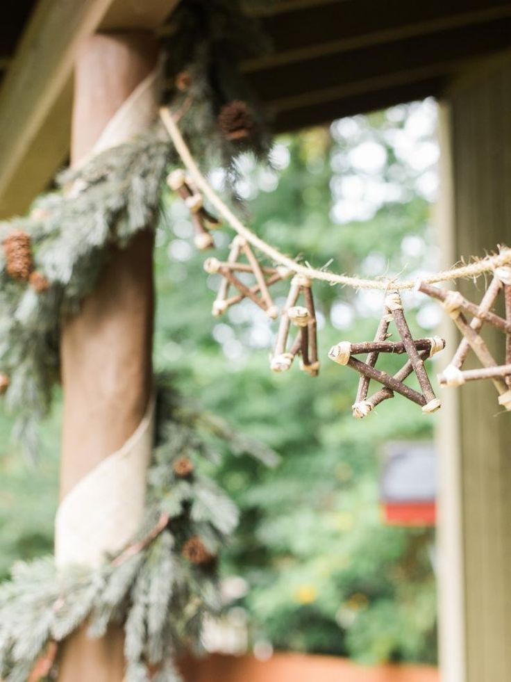 a christmas garland hanging from a porch with pine cones and starbursts on it