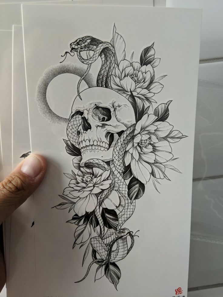 a person holding up a piece of art with flowers and a snake on it's head