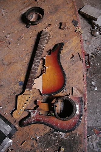 an old guitar is laying on the floor with it's pick up tools nearby