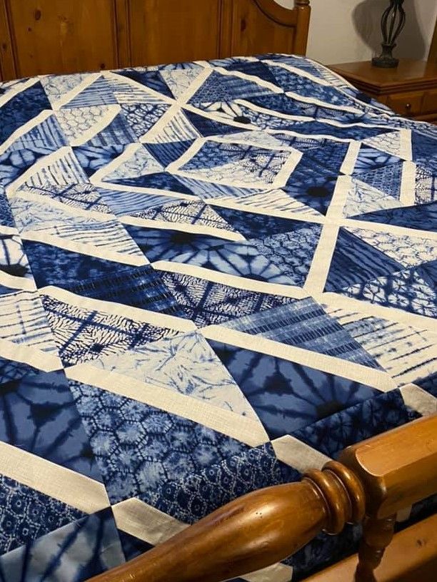 a bed with blue and white quilt on it