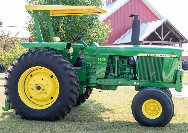 a large green tractor parked on top of a lush green field