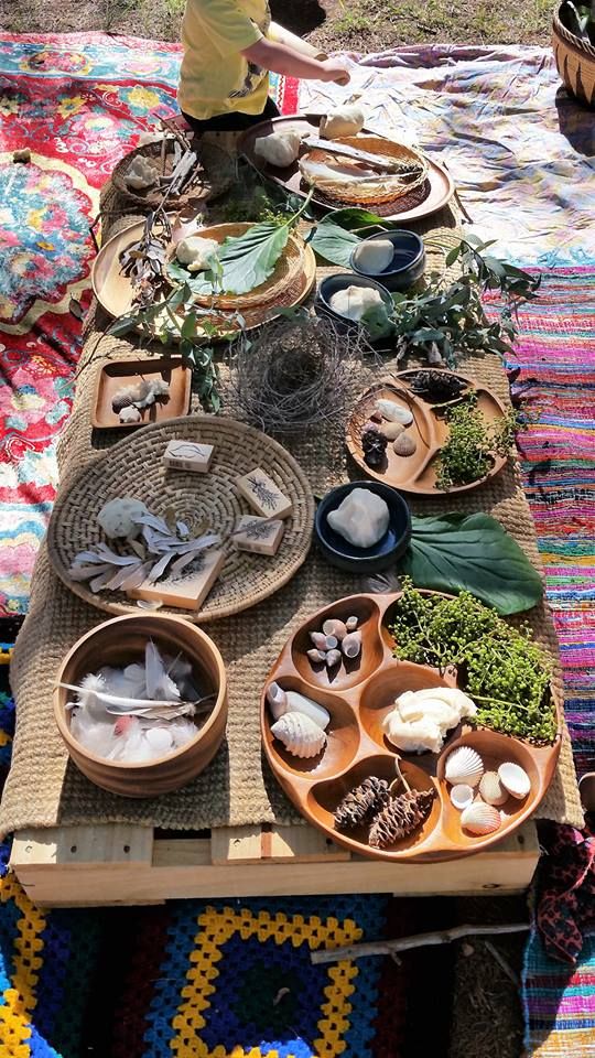 a table topped with lots of plates and bowls filled with food on top of a colorful blanket